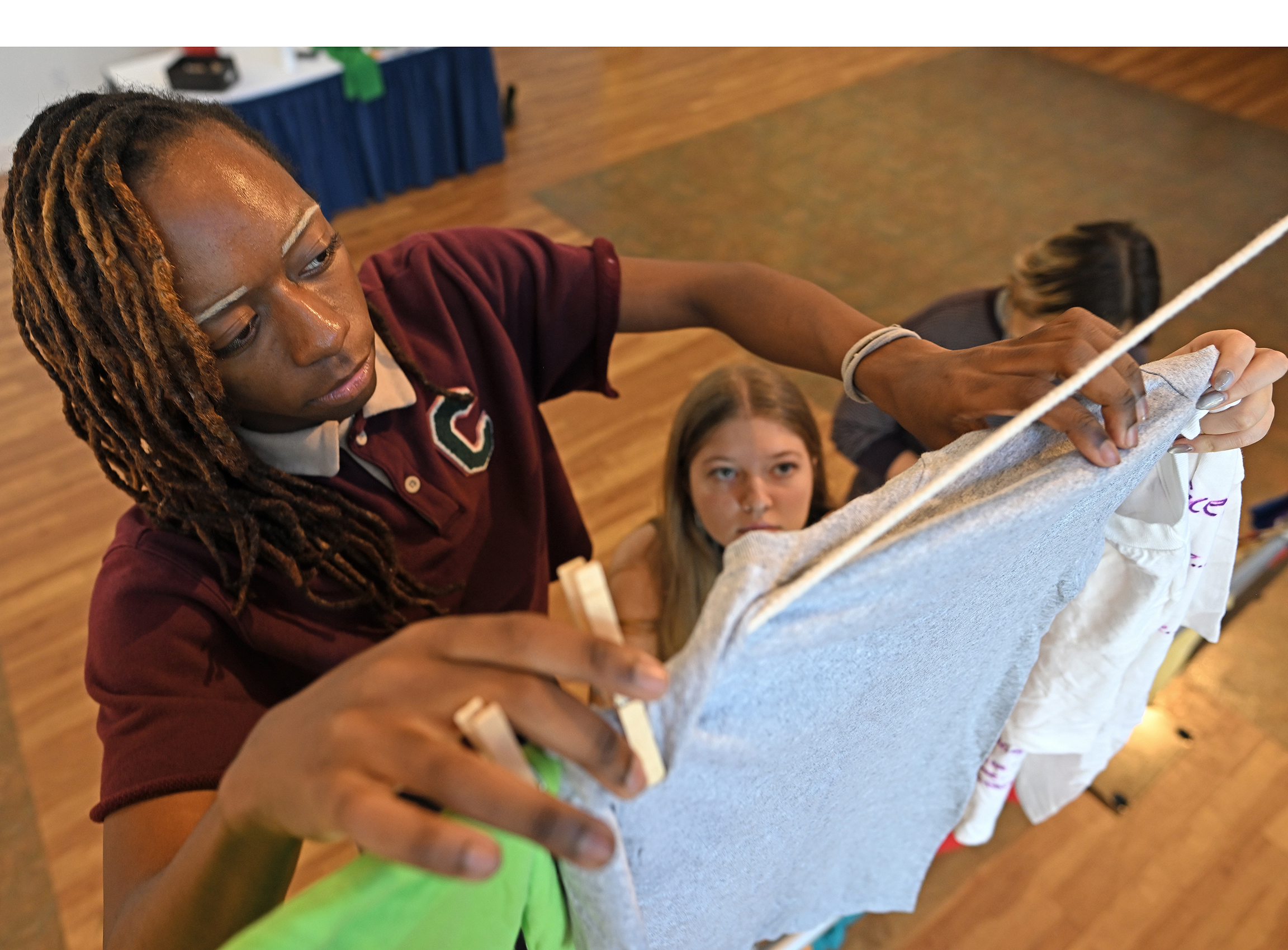 A student uses clothespins to hang t-shirts for a domestic violence awareness event.