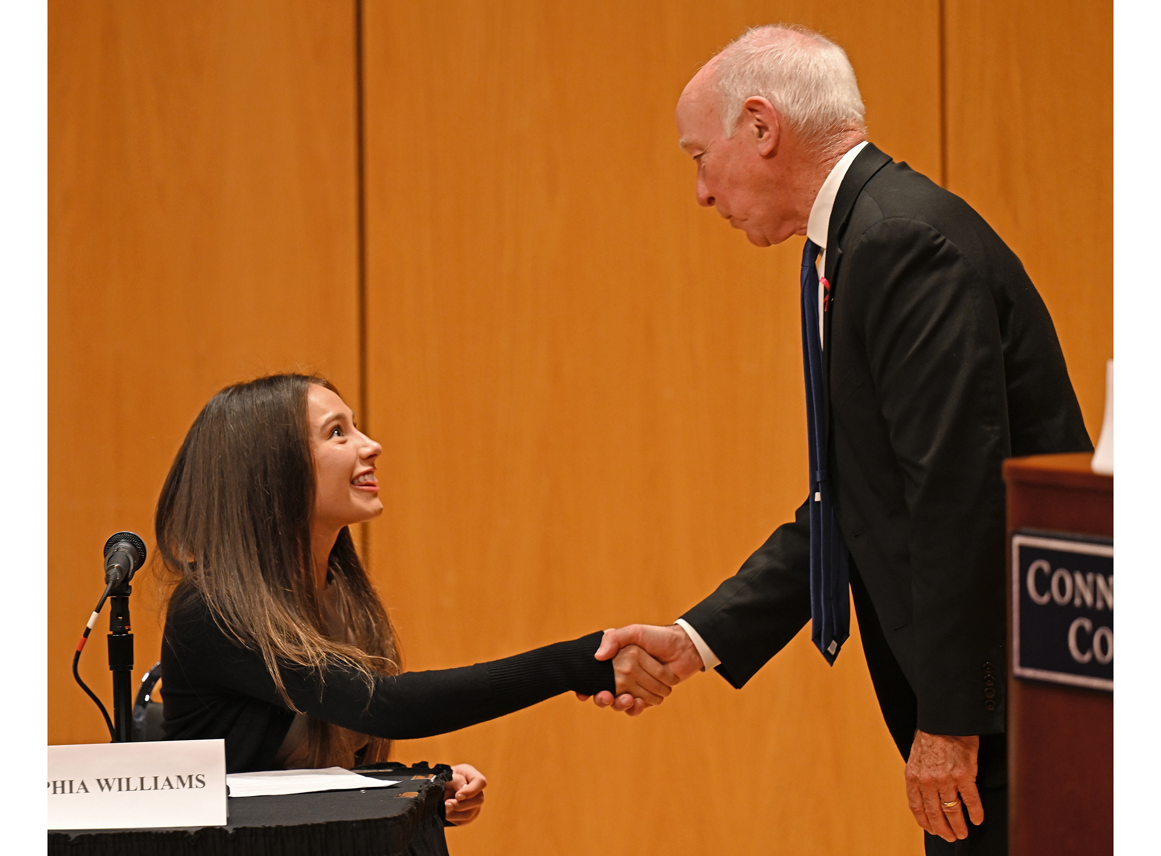A student shakes hands with a congressman after a debate.