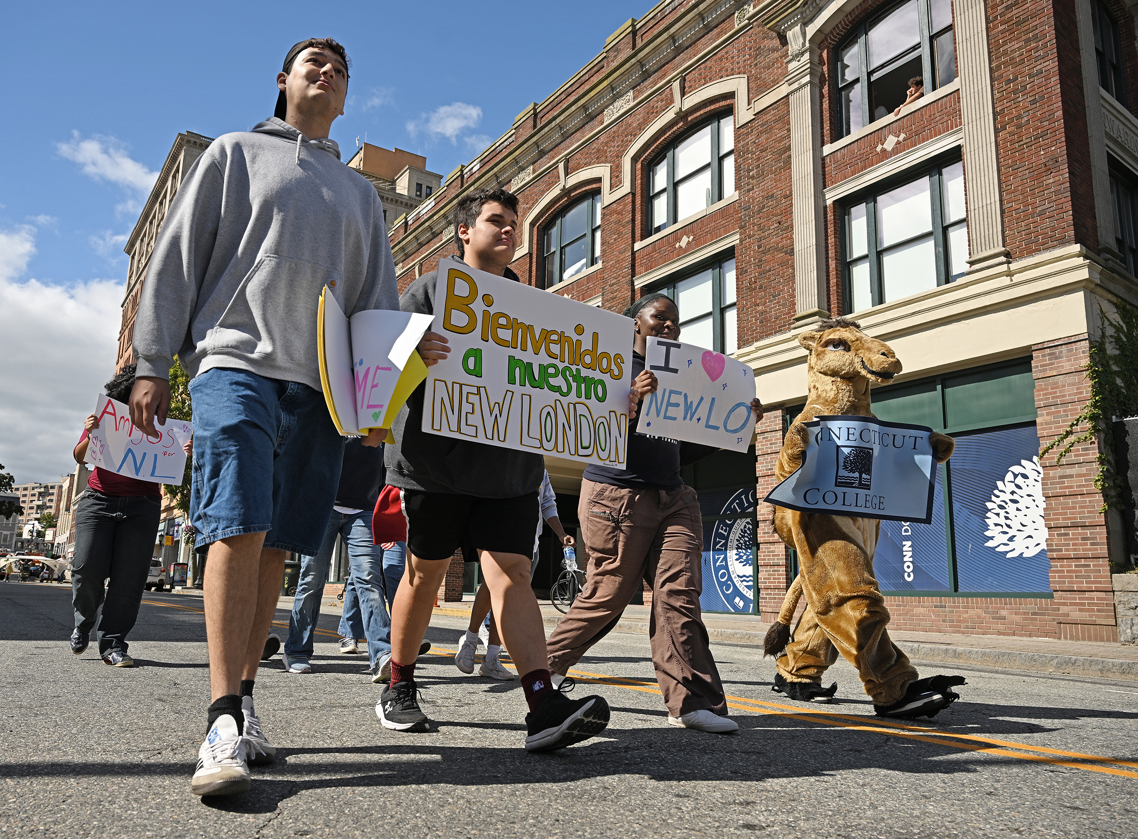 Students carrying banners, and one in a camel costume, march in a parade