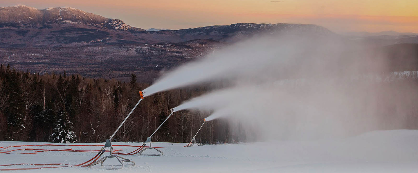 Snowmaking equipment sprays snow on a mountainside.