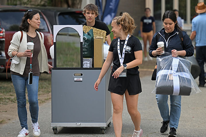 A new student and family members transport the student's belongings to the residence hall.