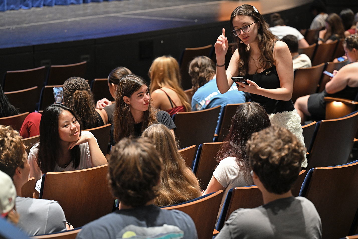 A student makes a campaign pitch to others during an orientation assembly on a college campus.