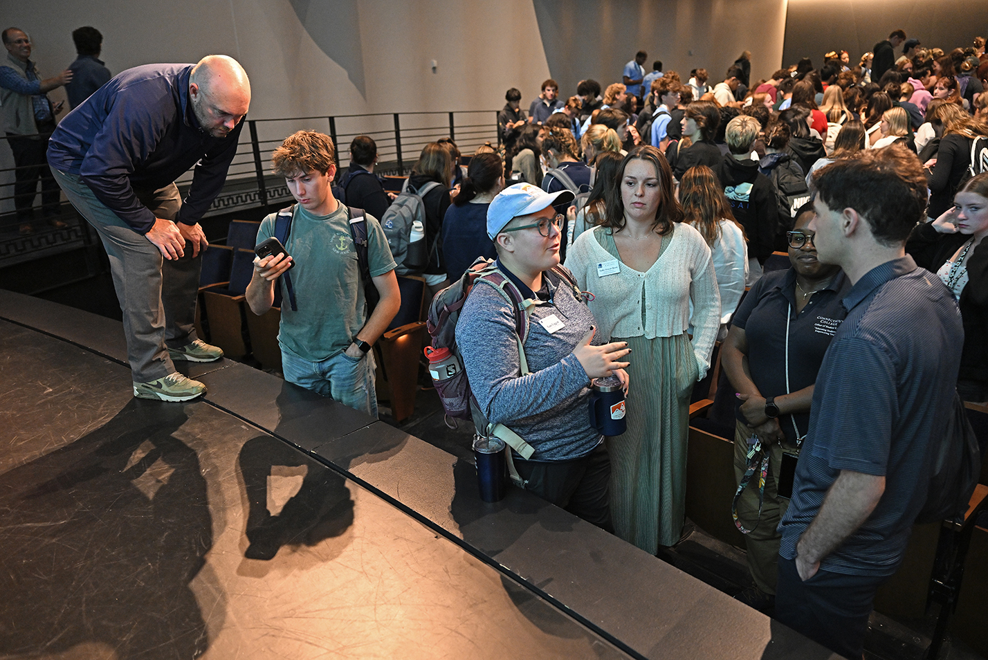 first year college students as questions of the staff during an orientation session in an auditorium.