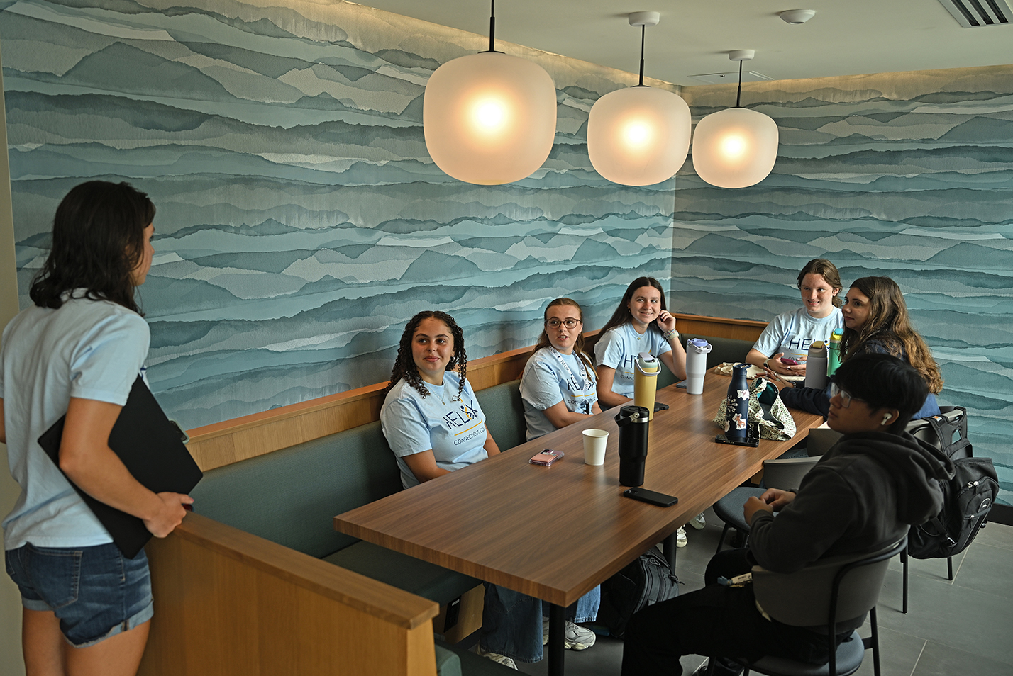 A small group of first year college students gather around a dining hall table for an orientation meeting.