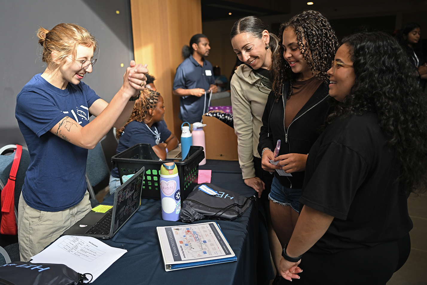 A student orientation leader greets a student and their family checking in for college.