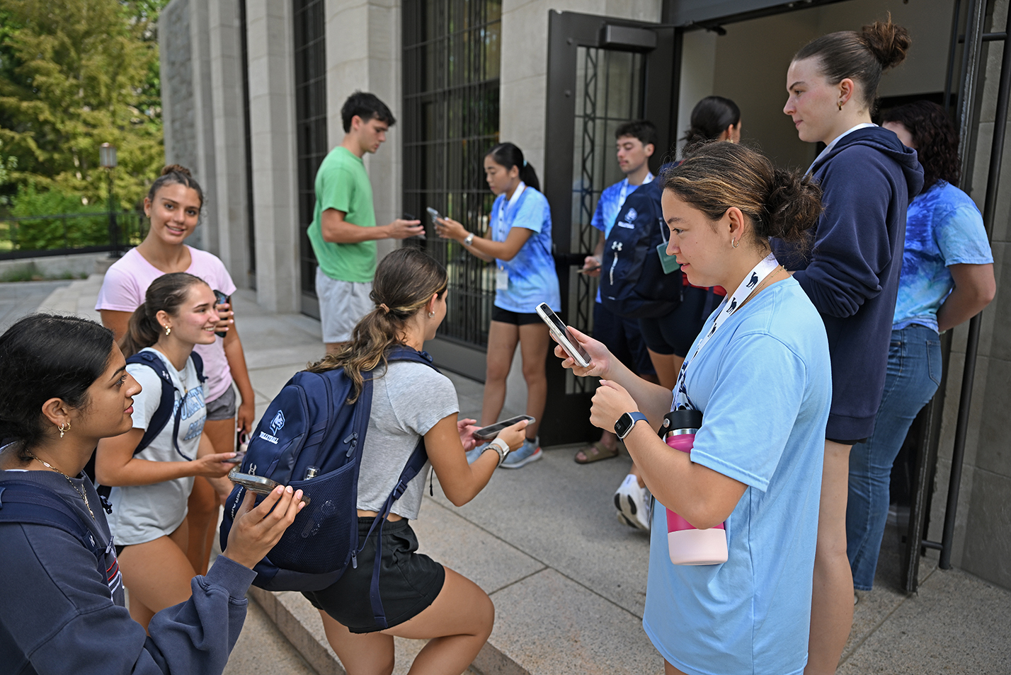 Student advisers at the door to an auditorium check first year students in to an orientation session using smart phones.