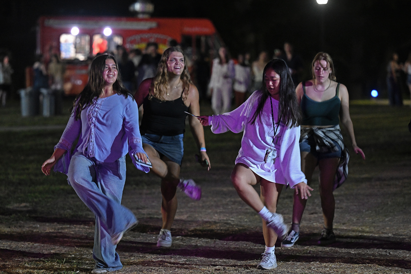 Students dance the Electric Slide during an outdoor block party on a college campus.