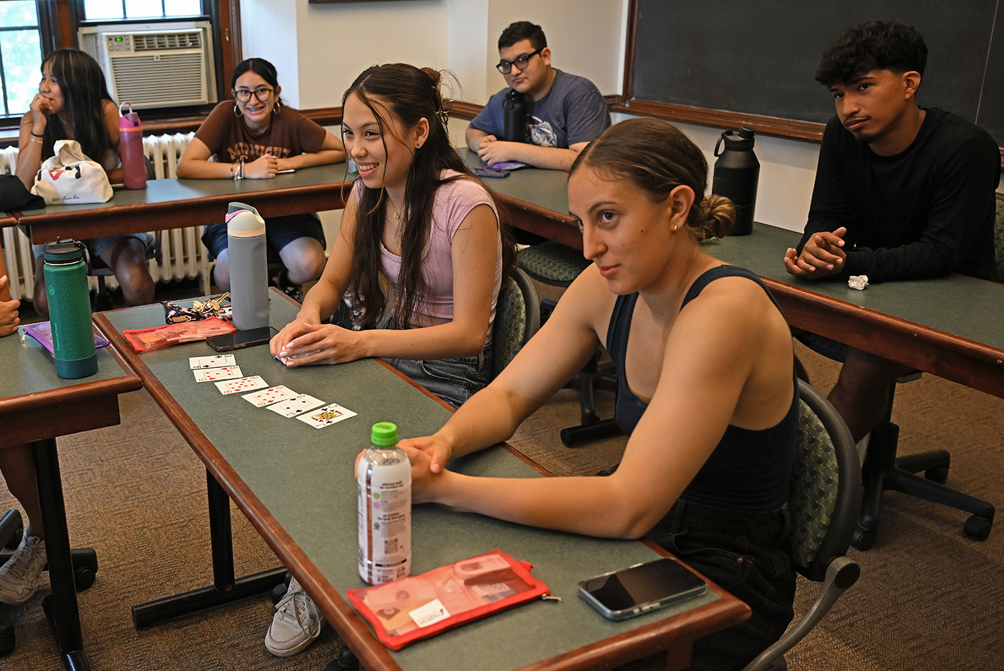 College students smile as they react to a math-based card trick in a classroom.