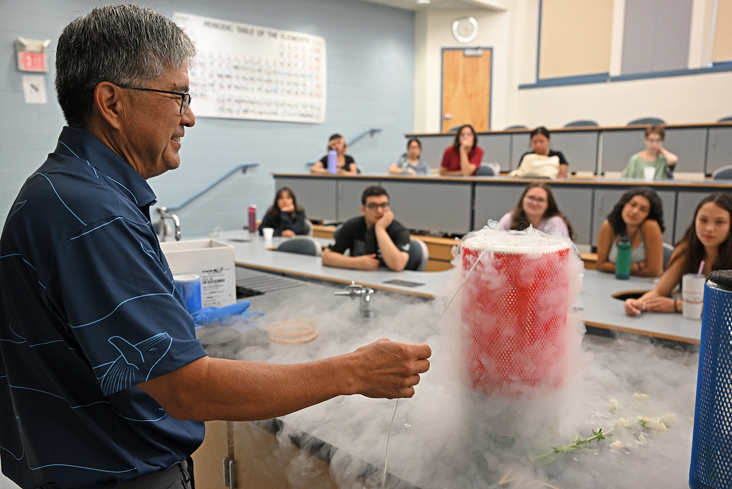 A college professor immerses a banana in a flask of liquid nitrogen sending out waves of fog over a tabletop.