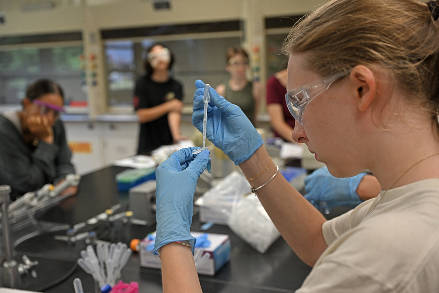 A college student uses a dropper to add liquid to a test tube in a chemistry laboratory.