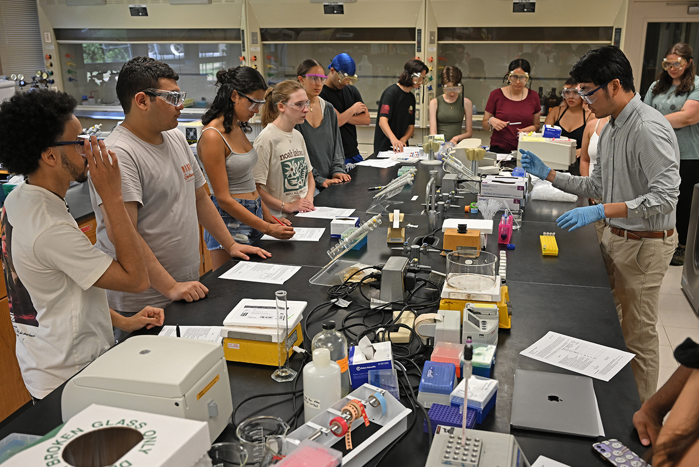 A college professor leads a group of students in a chemistry experiment.