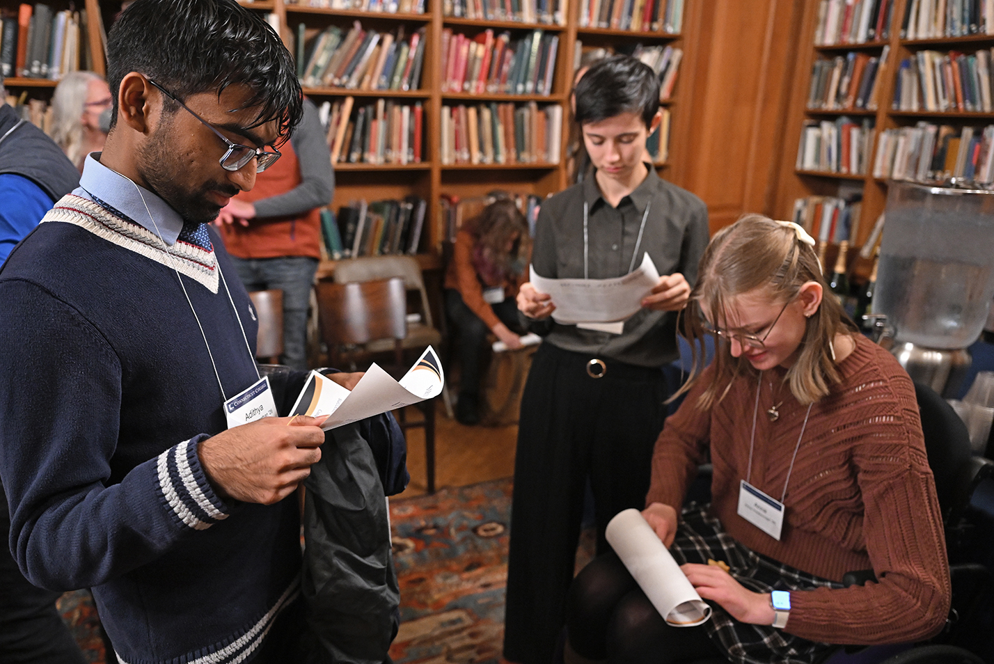 Early-graduating students unroll certificates presented to them during a celebration of their accomplishment.