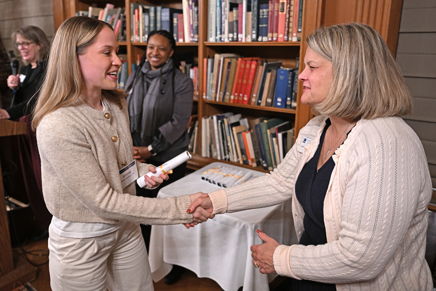An early-graduating college senior shakes hands with the college president during a celebration of the event.