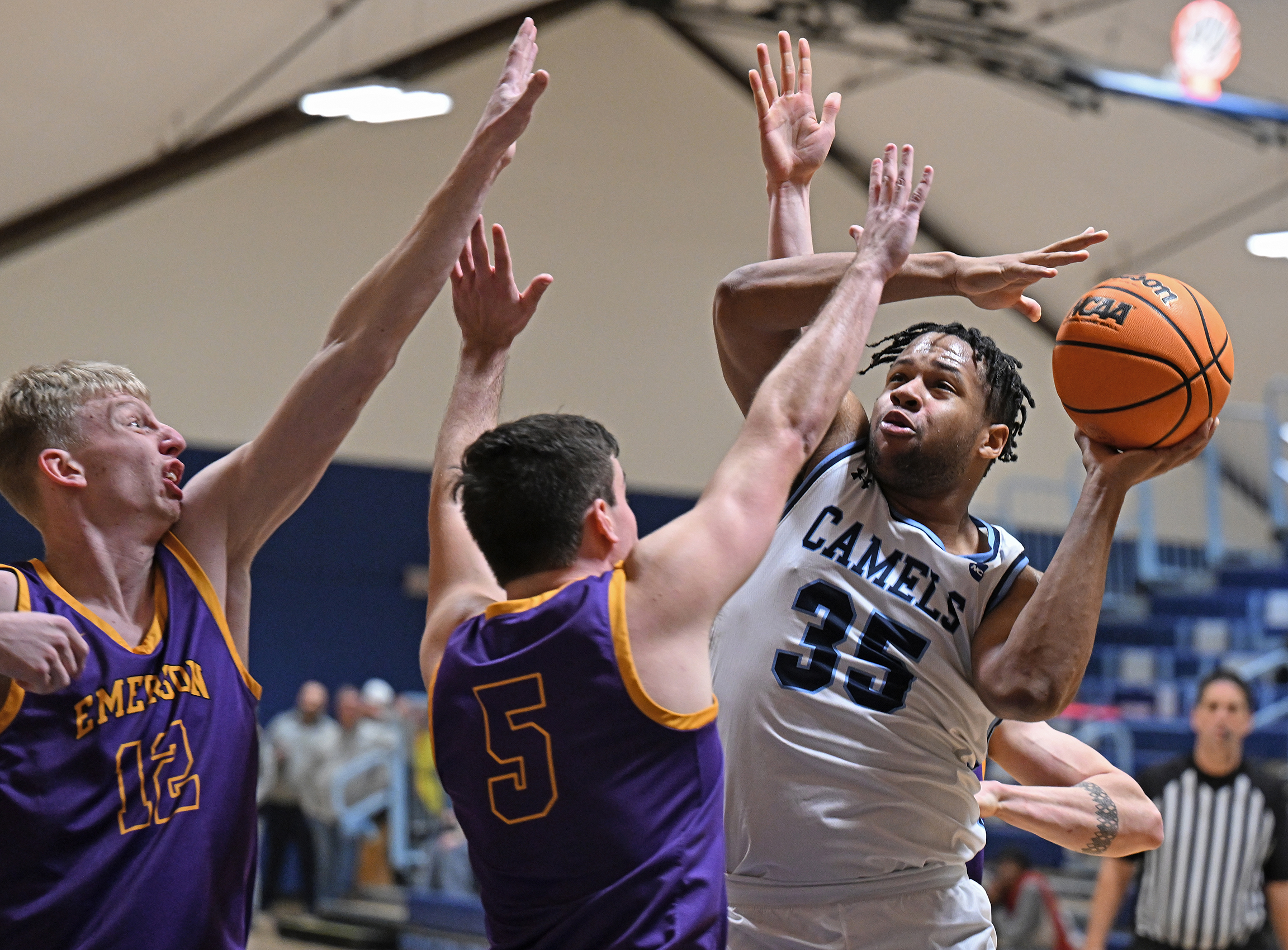 A basketball player goes up fro a shot against two defenders.
