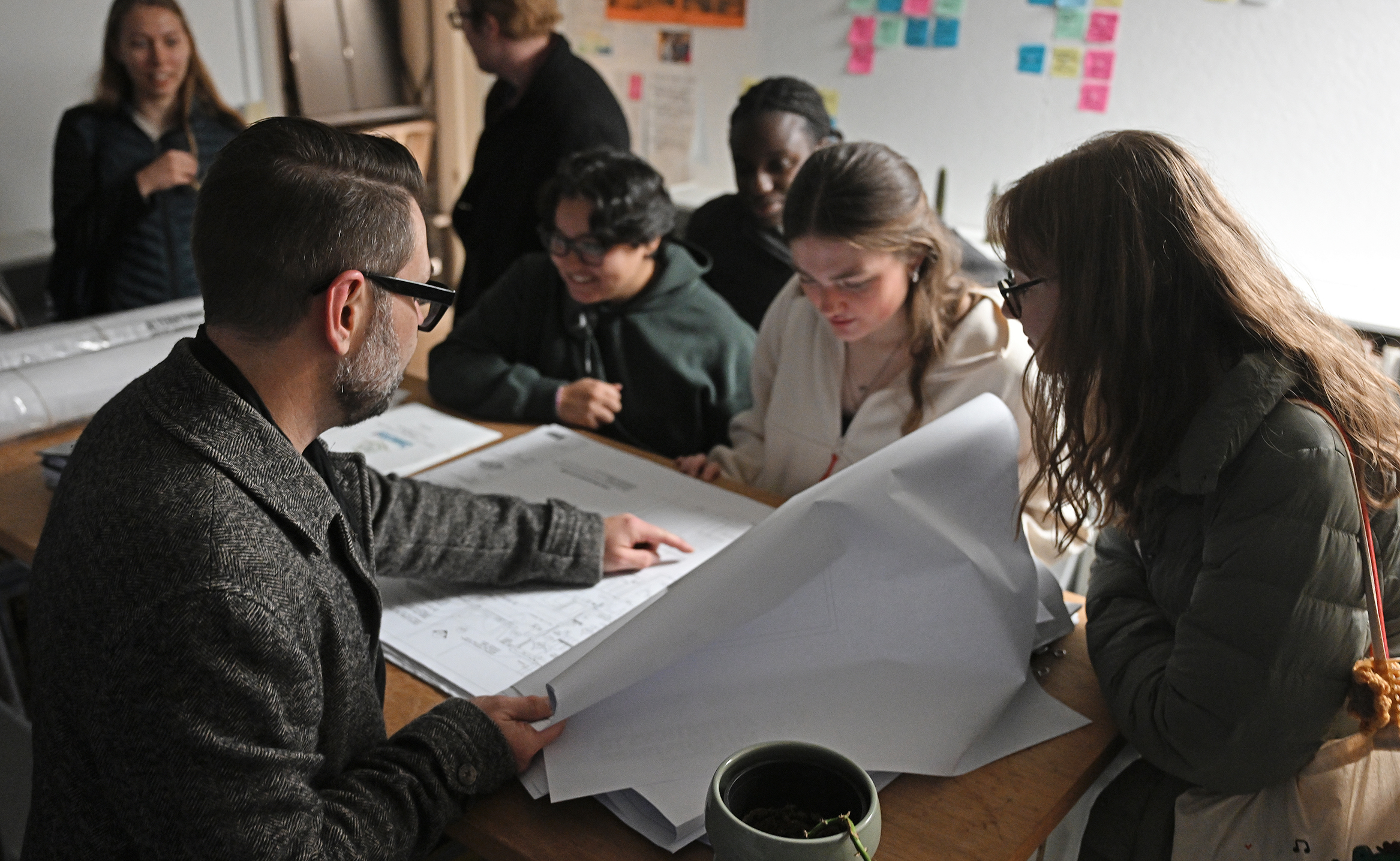 An architect points out features in a building plan to college architecture students.