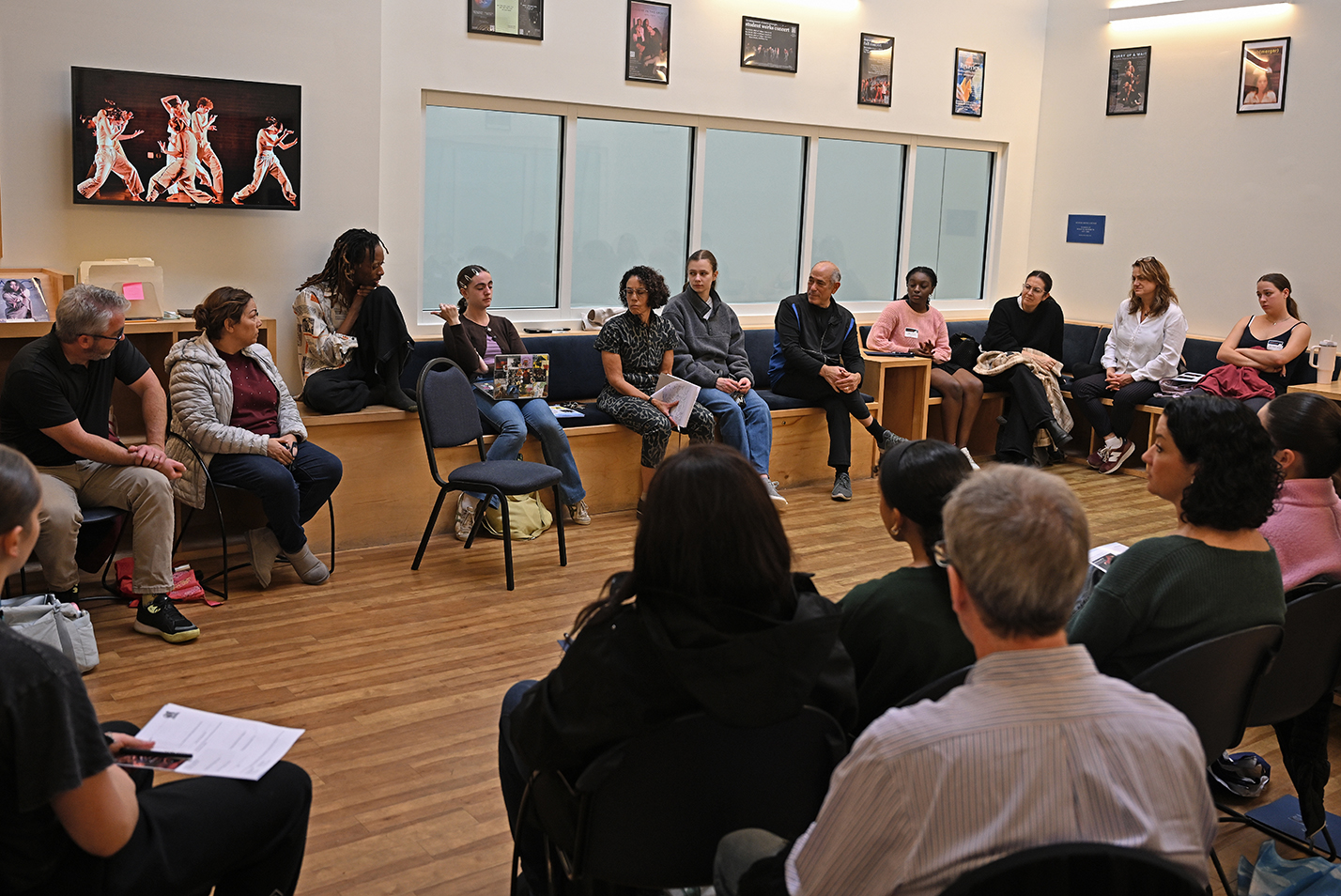 Prospective college students gather in a dance studio lounge, with photos of dancing performances on display, to hear from faculty and students.