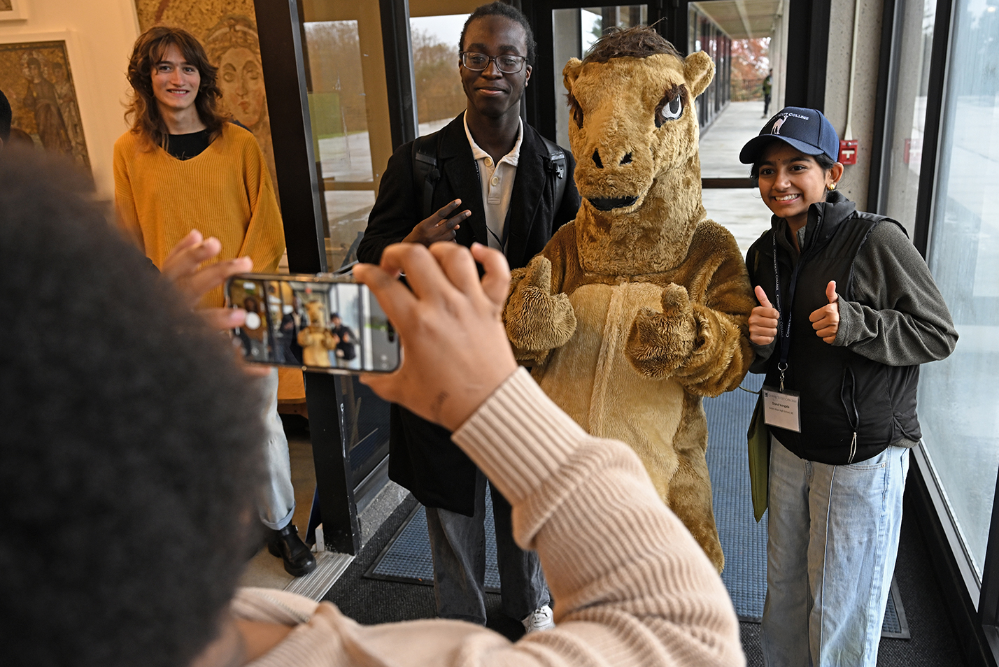 Prospective college students take a photo with a college camel mascot during an open house event.