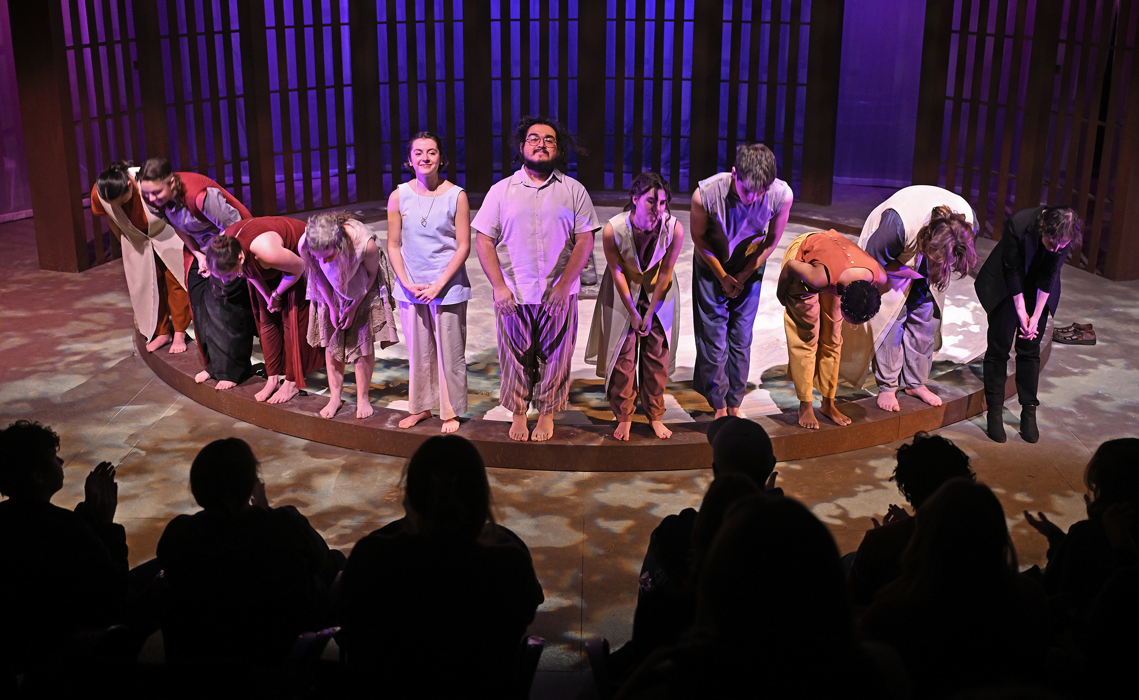 The cast of a play takes a curtain call in a black box theater.
