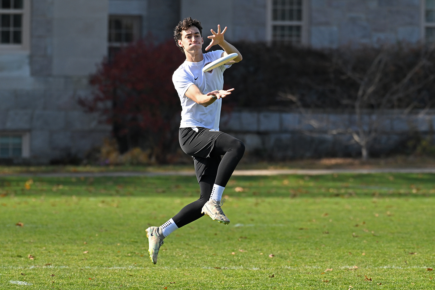 A student leaps into the air to catch a flying disc during an Ultimate Disc tournament.