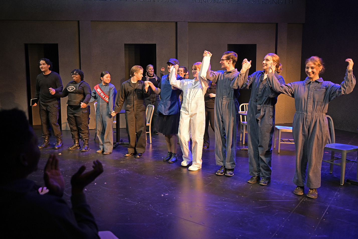 College theater students hold hands as they take the stage for a curtain call after a play.