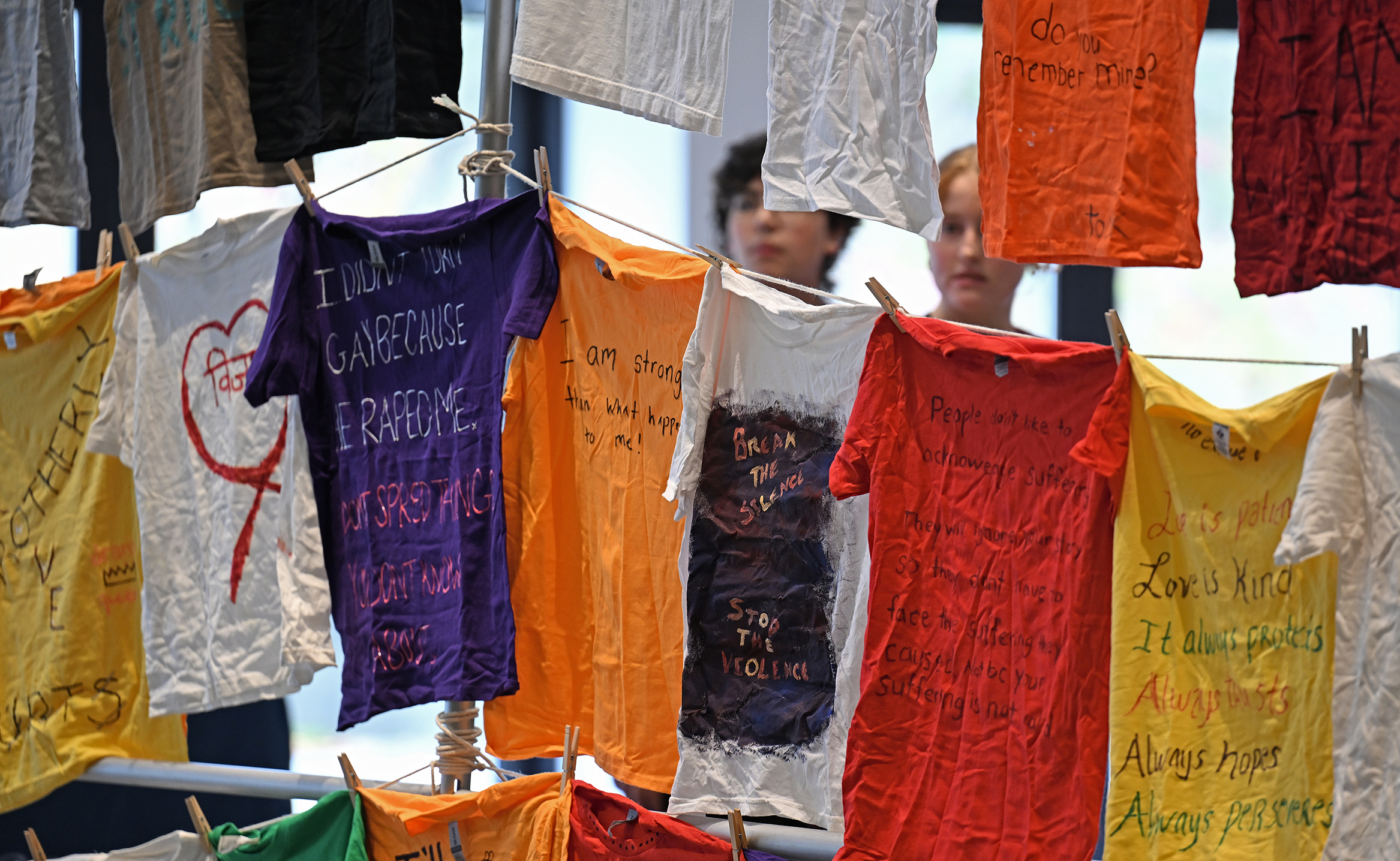 Students look at colorful t-shirts with anti-sexual violence slogans written on them.