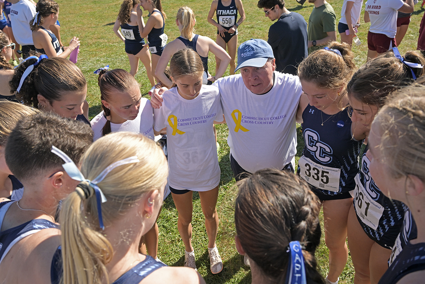 A coach huddles his cross country runners in a circle for a pre-race pep talk.