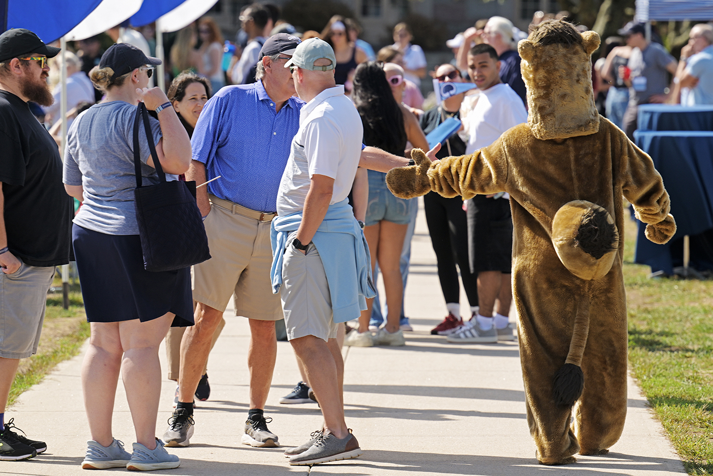 A college camel mascot high fives a fan during a college soccer match.