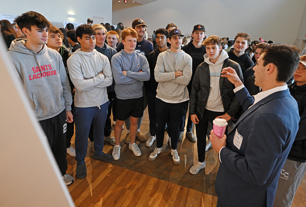 A student explains his poster at the All College Symposium