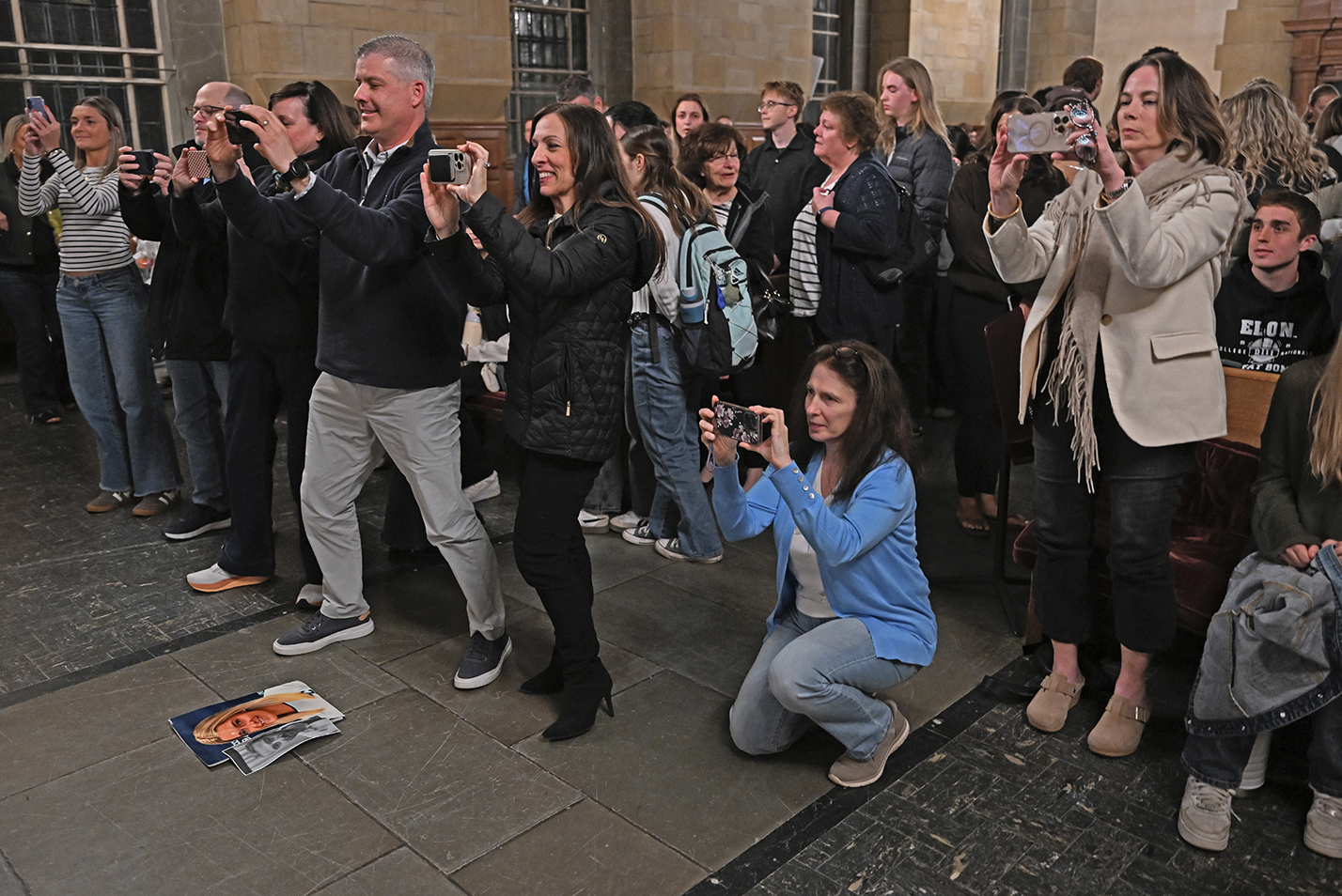 Family and friends in the audience gather to take photos following an a cappella group performance.