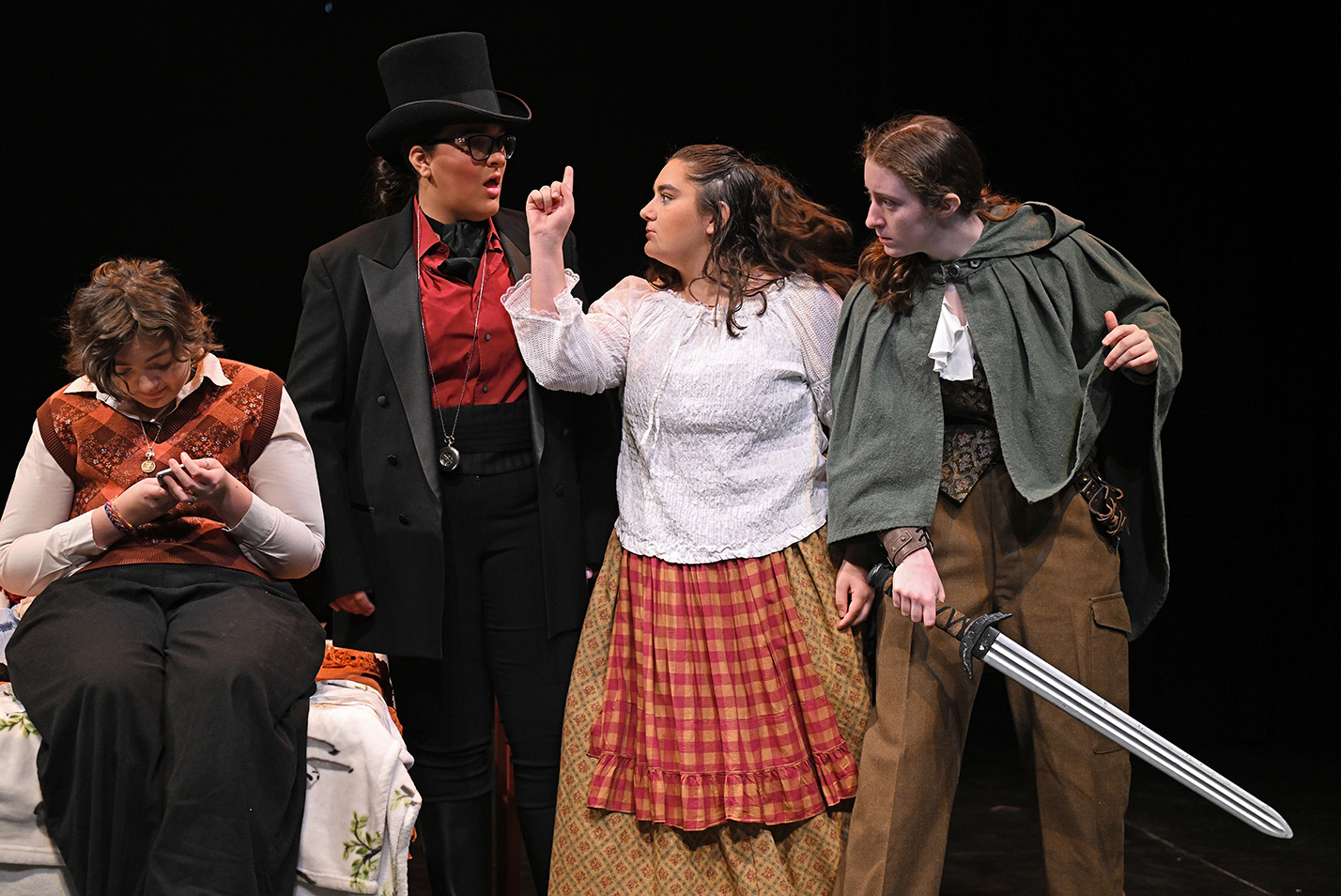Four college acting students, one in contemporary clothes, the others in renaissance fair costumes perform a scene on stage in a black box theater.