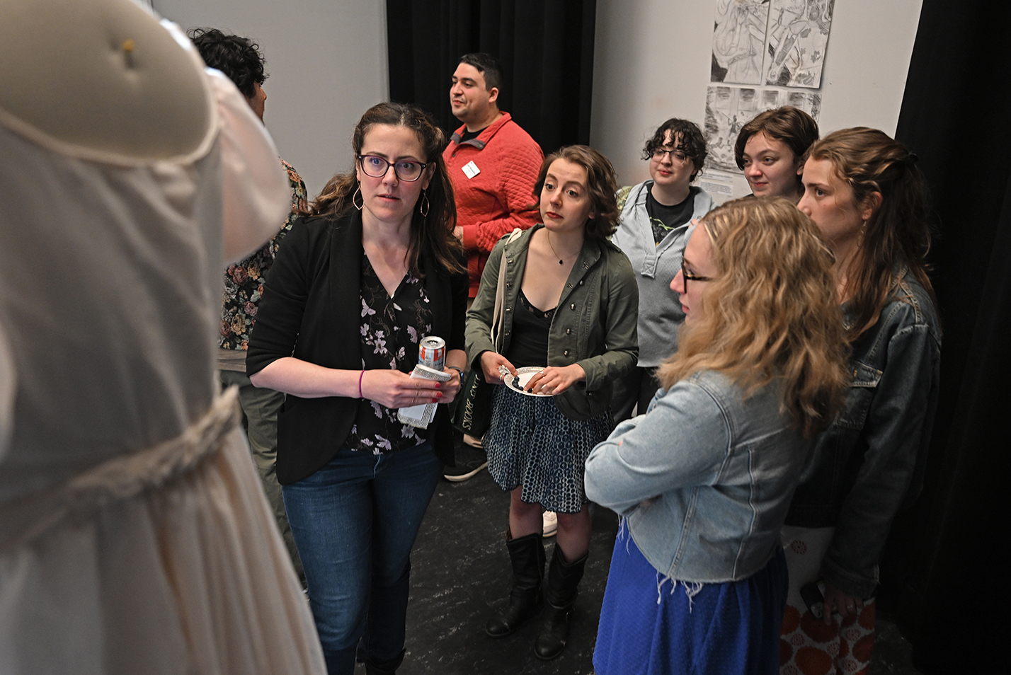 A group stands together looking at a theater costume on display in a theater space turned art gallery.