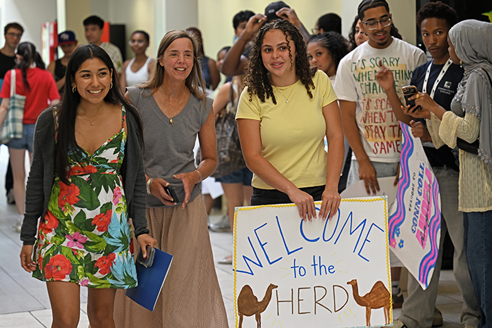 Student leaders hold welcome signs as new students enter Cro.