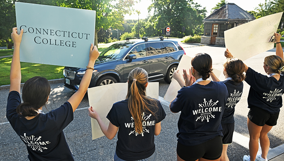 Student leaders cheer and hold up signs welcoming new students.