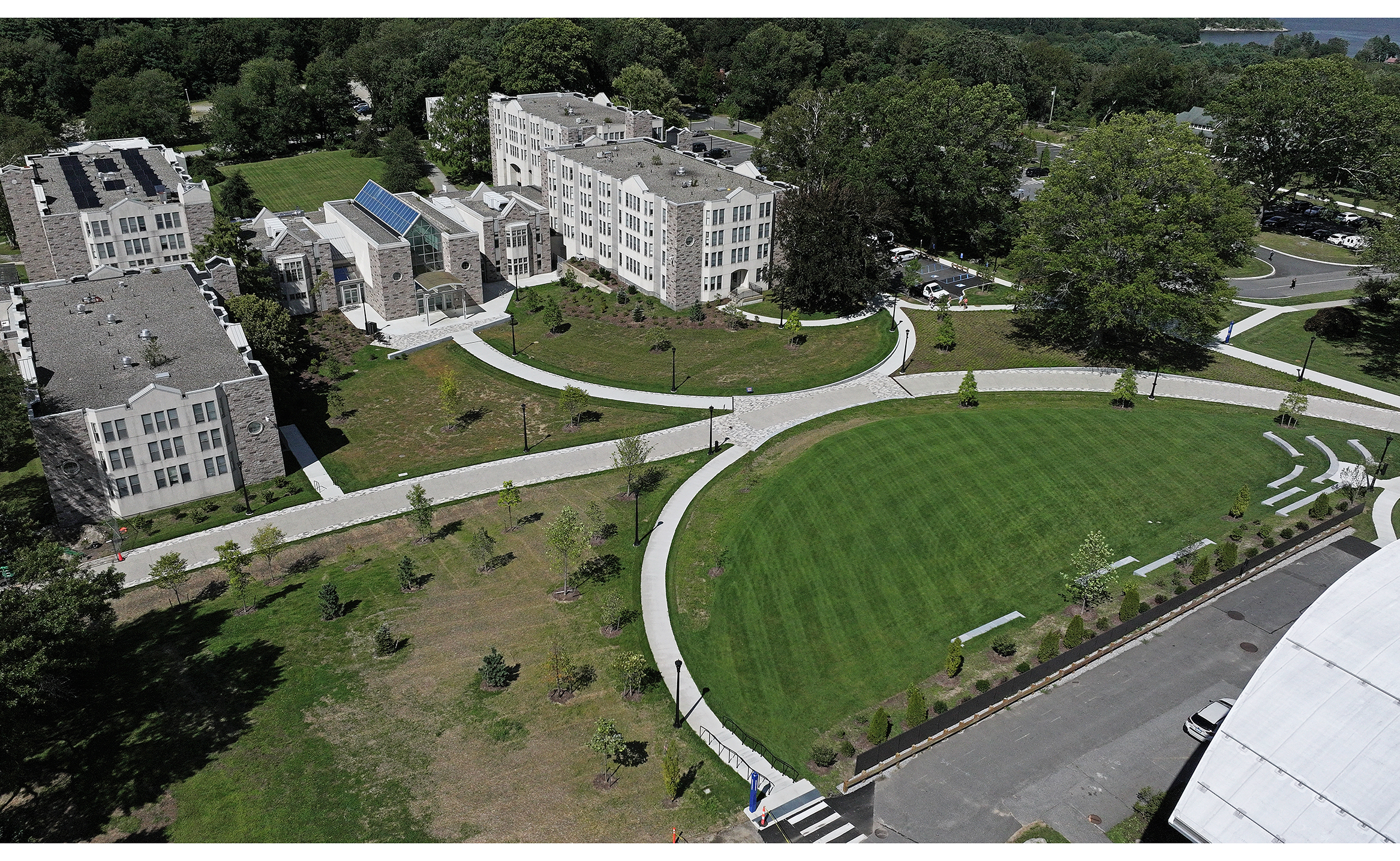 Aerial view of a college campus with granite residence halls to one side an walkway framed green areas to the other.