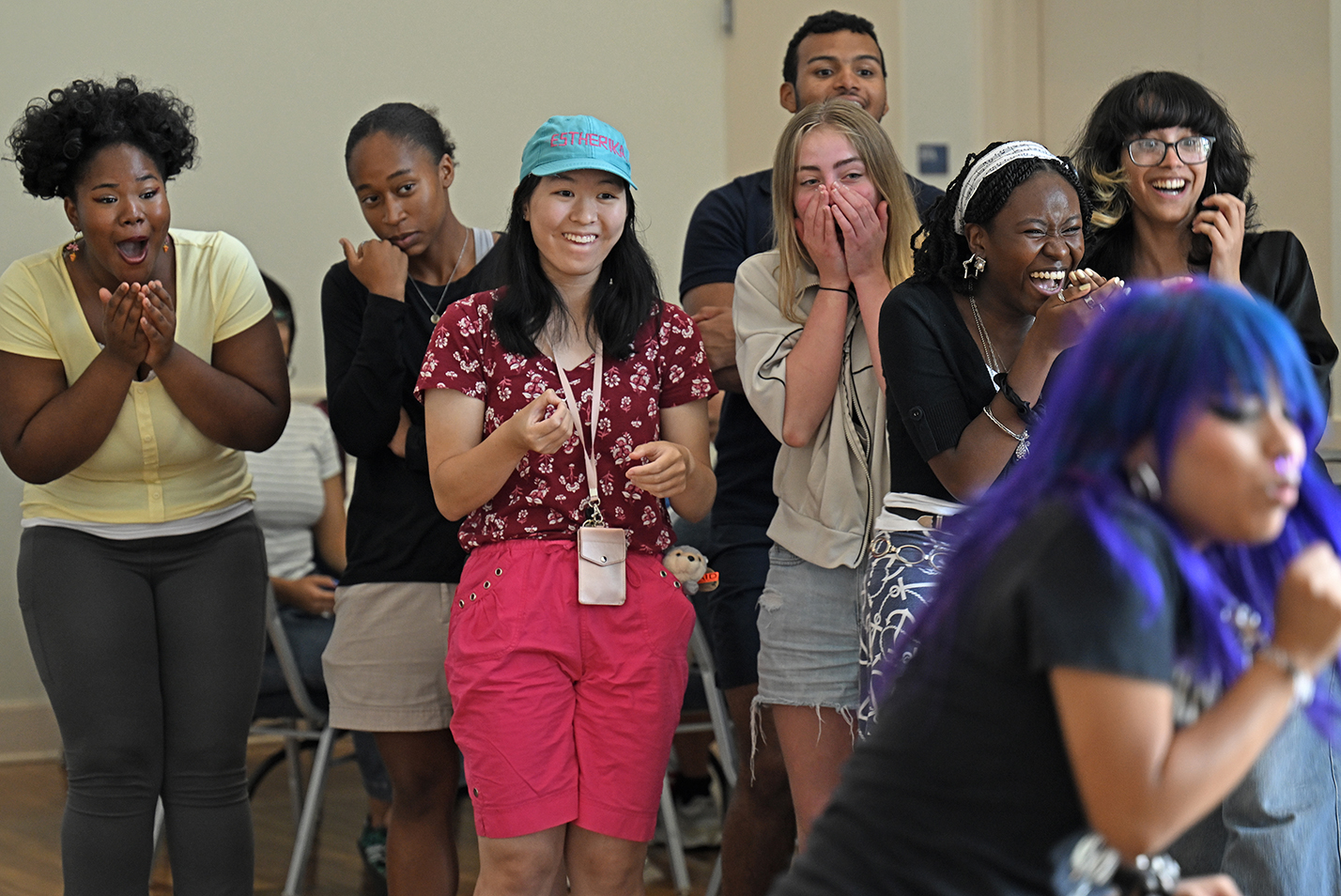 A group of college students make faces as they react to activity out of view.