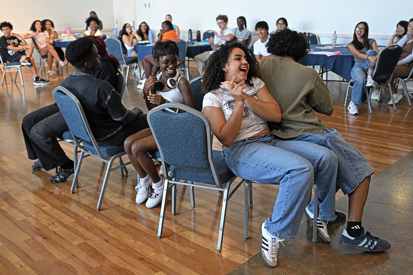 College students laugh as they battle for a spot during a game of musical chairs.
