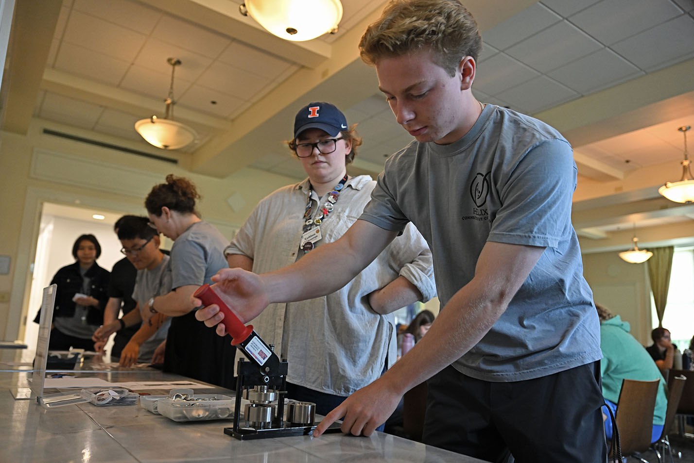 A college staffer helps a first-year student use a button-maker during an orientation session.