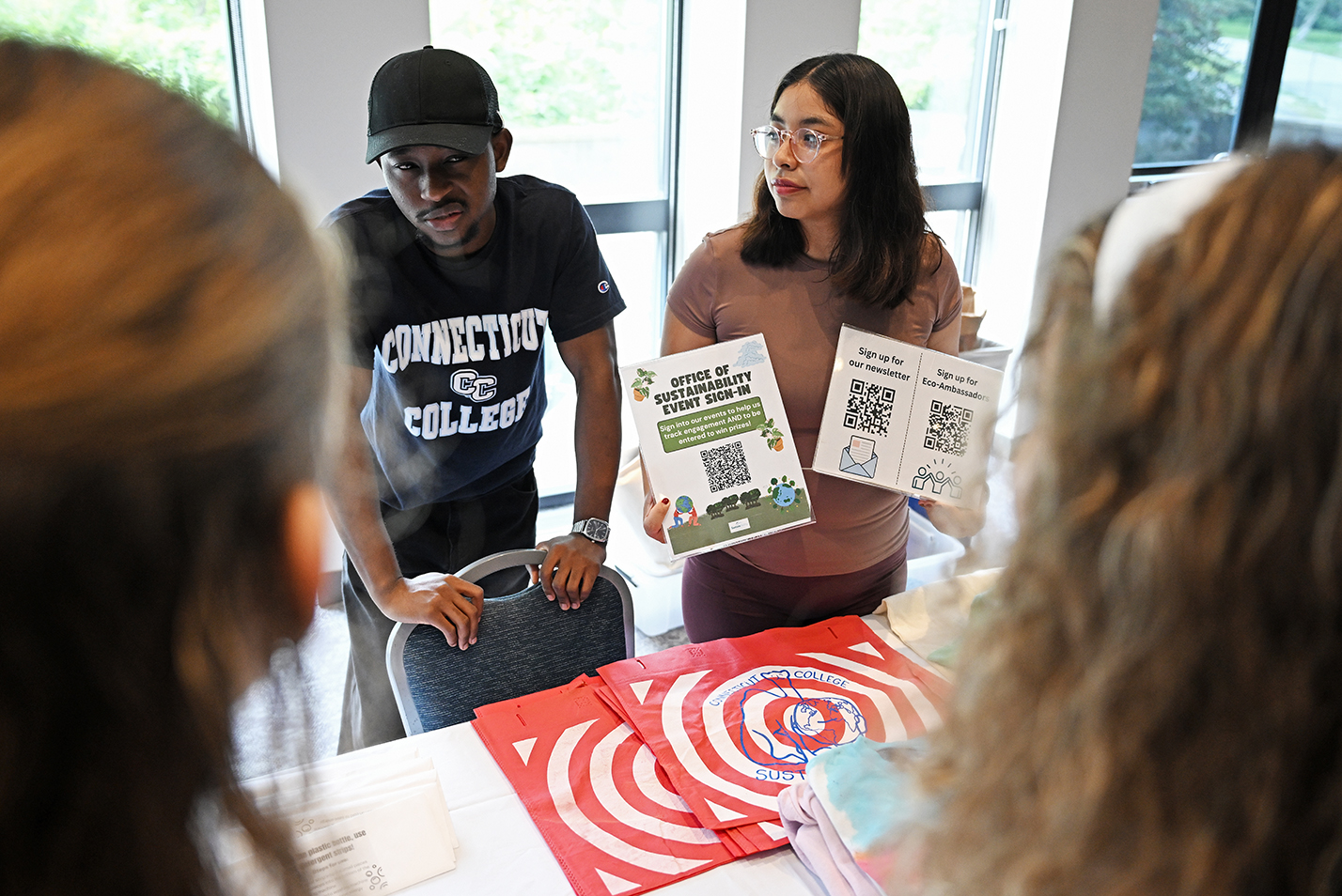 Two college students working at an information table speak to students.