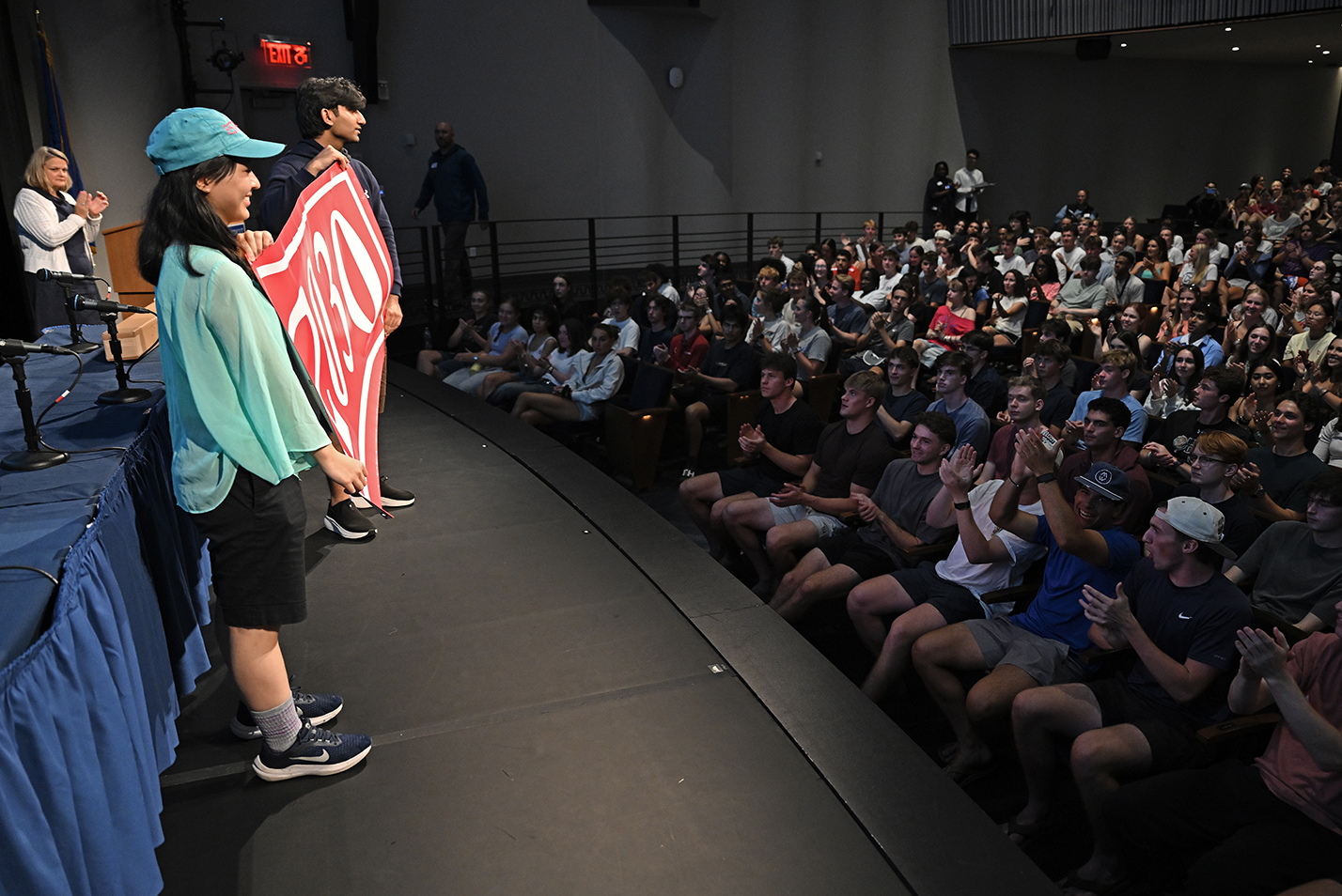 A pair of college students hold a bright red banner reading 