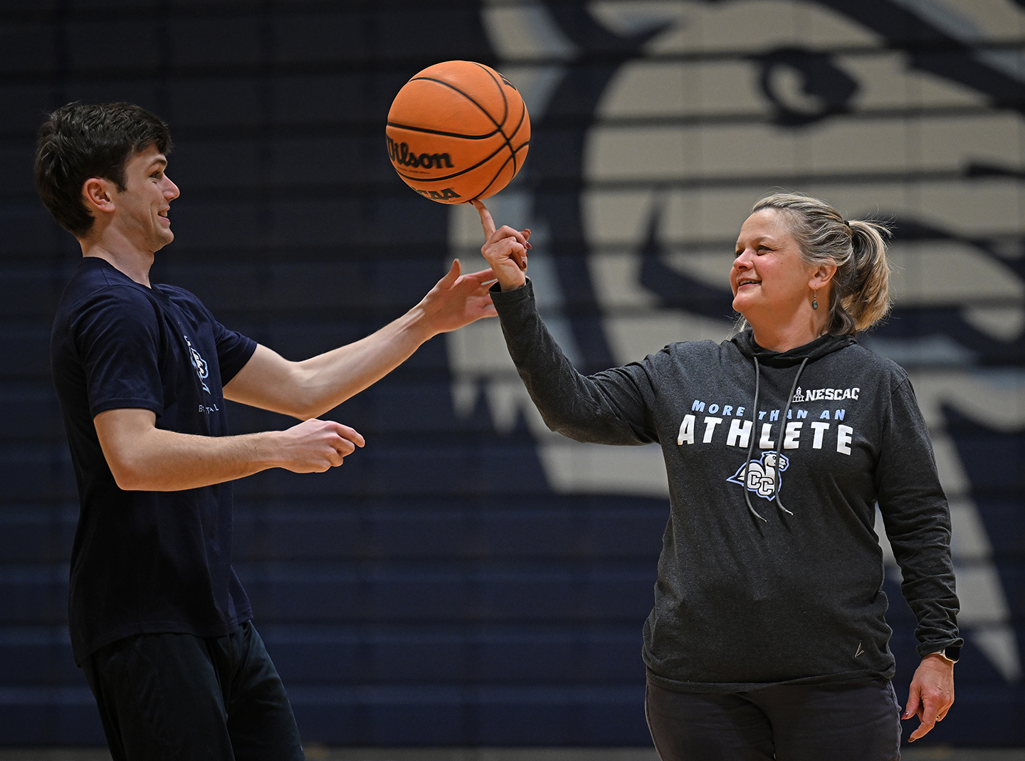 RJ Casey '26 teaches President Andrea Chapdelaine how to spin a basketball on her finger.