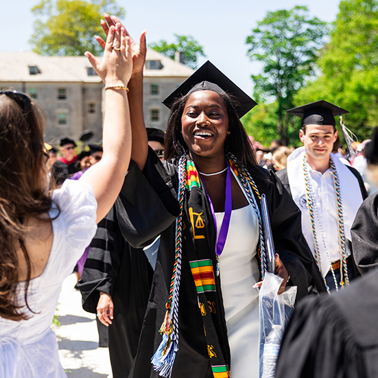 Senior speaker Zoe Watts high-fives a member of the audience at Commencement.