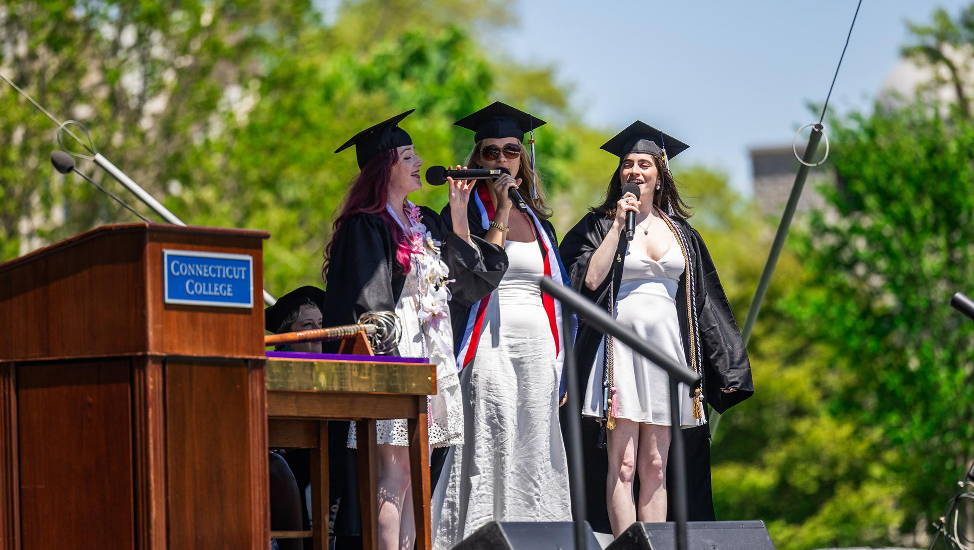 Three seniors sing the Alma Mater during Commencement.
