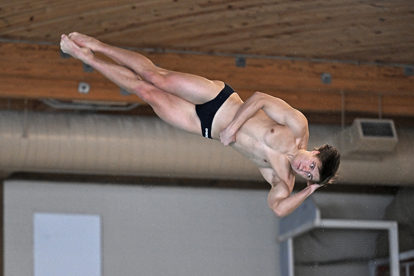 A male diver spins in the air after launching from the 3-meter springboard.