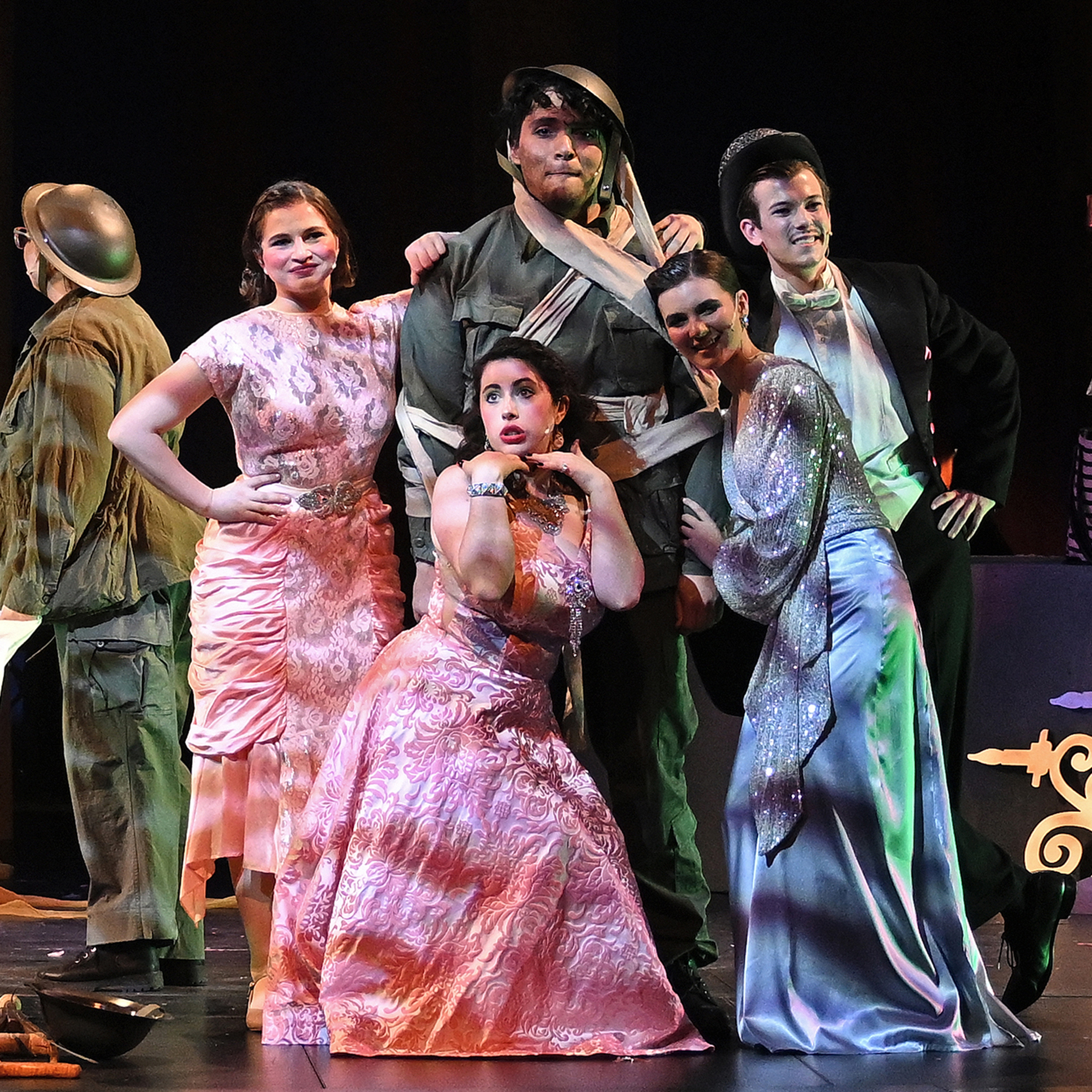 Student actors in colorful costumes perform a musical theater act on stage