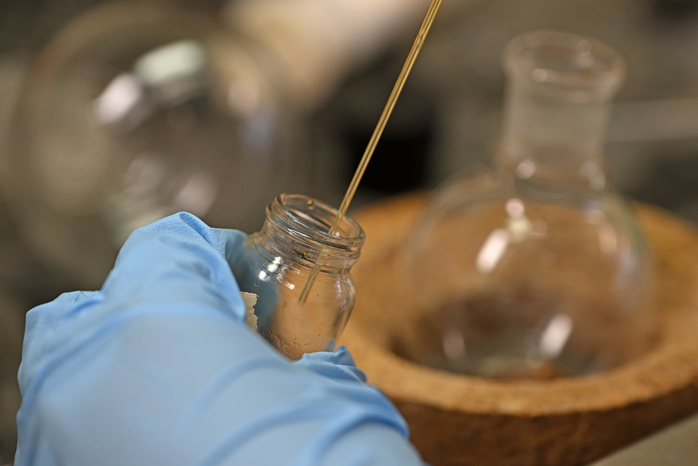 A lab distillation is transferred from one glass lab vessel into a smaller one.