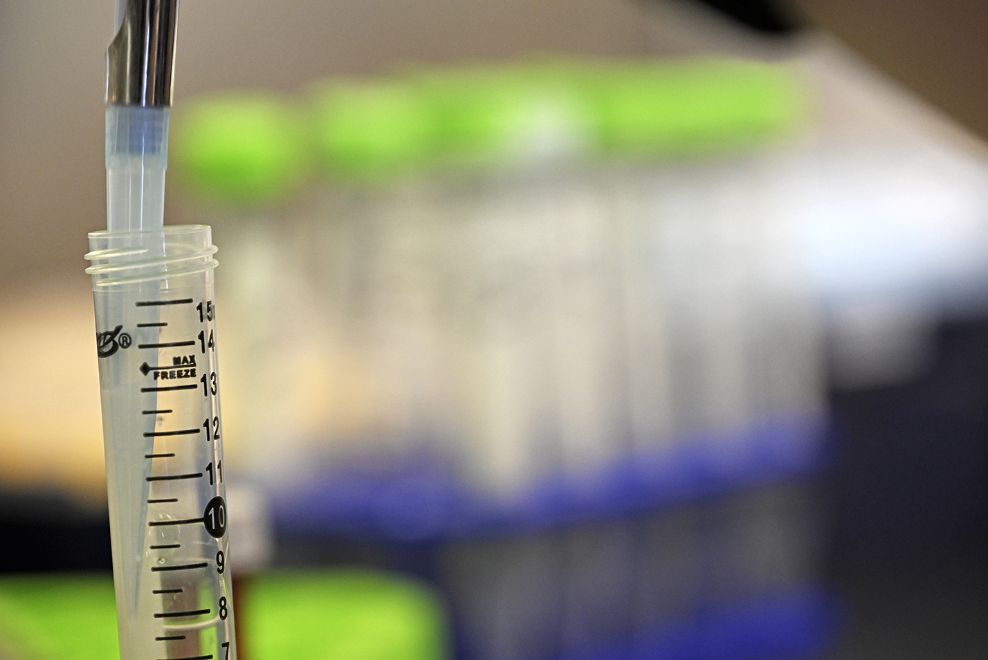 A plastic pipette is used to transfer liquid from one test tube to another in a chemistry lab.