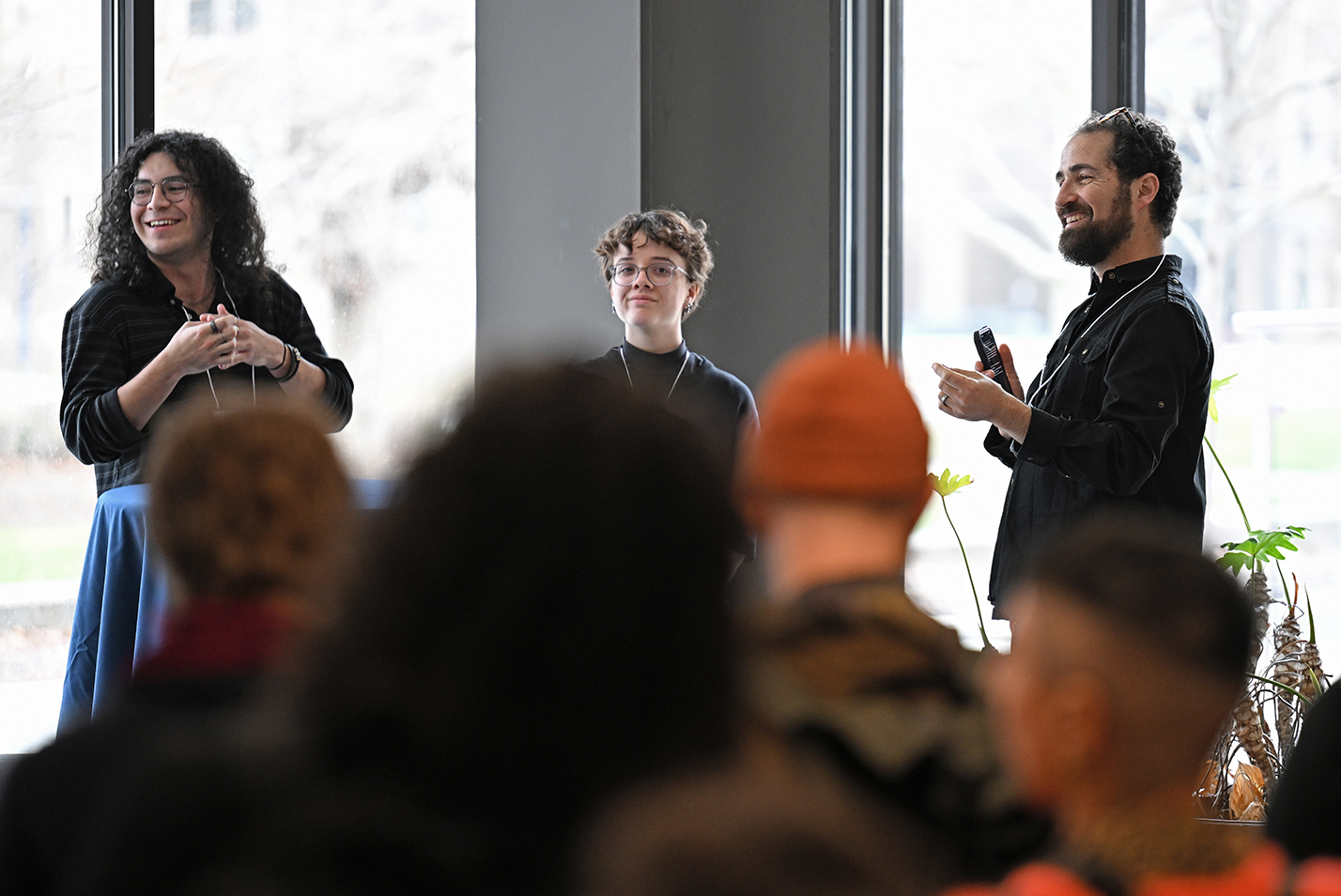 A professor introduces two student fellows to a reception gathering.