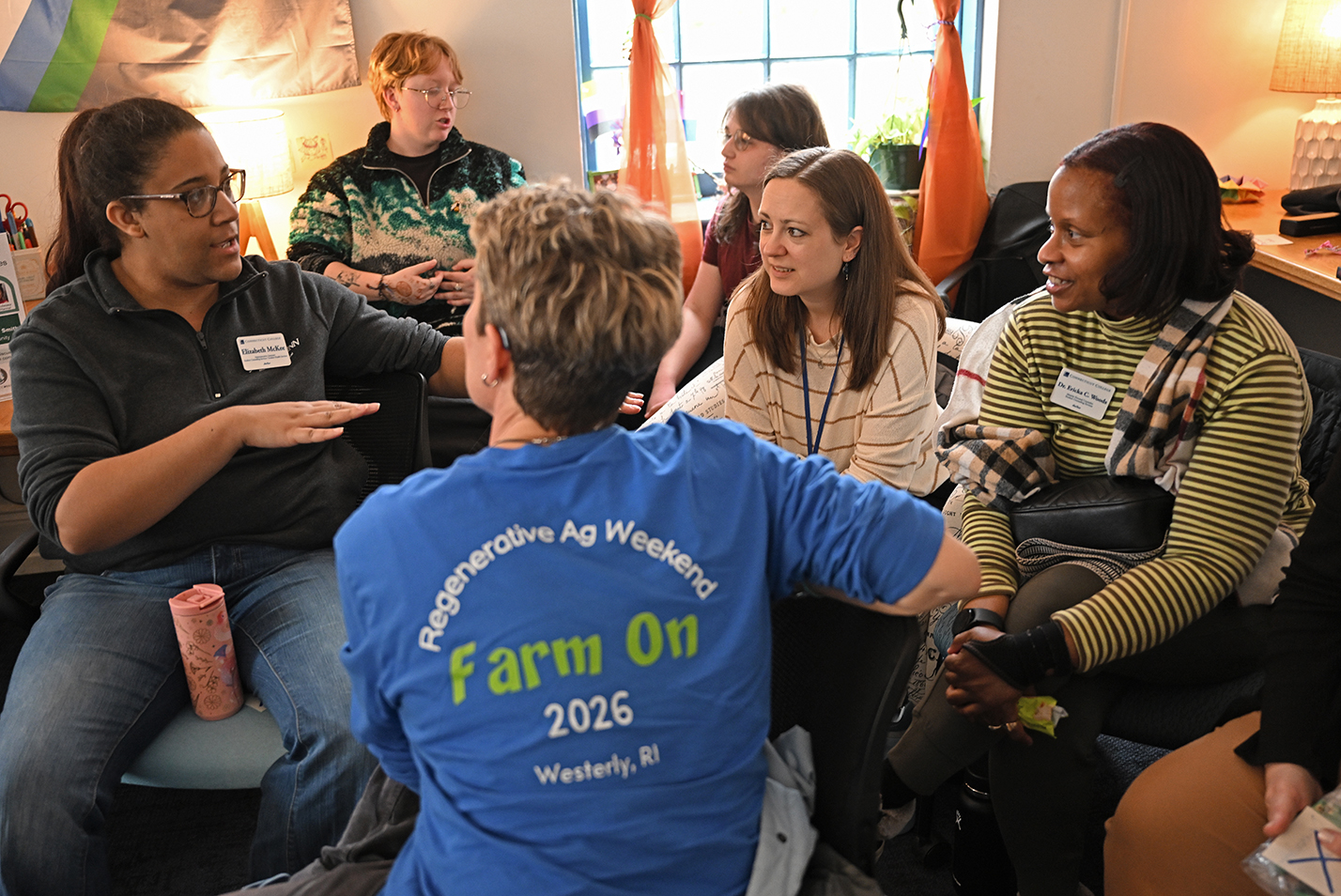 A group of college students, faculty, and staff, speak in a small group gathering.