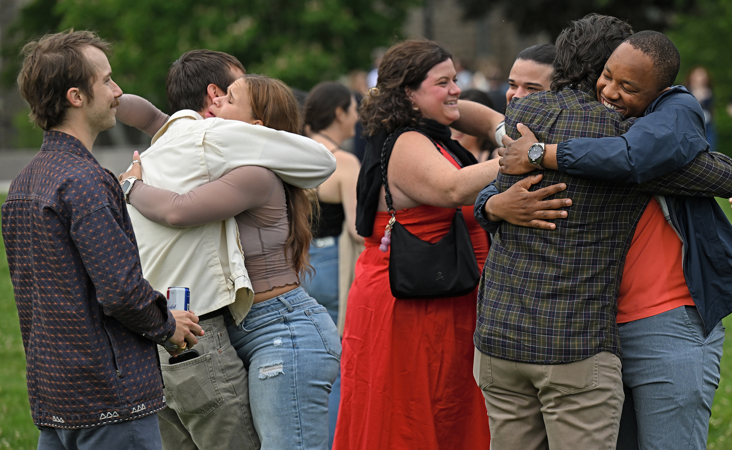 A group of young-adult college alumni embrace at a reunion event.