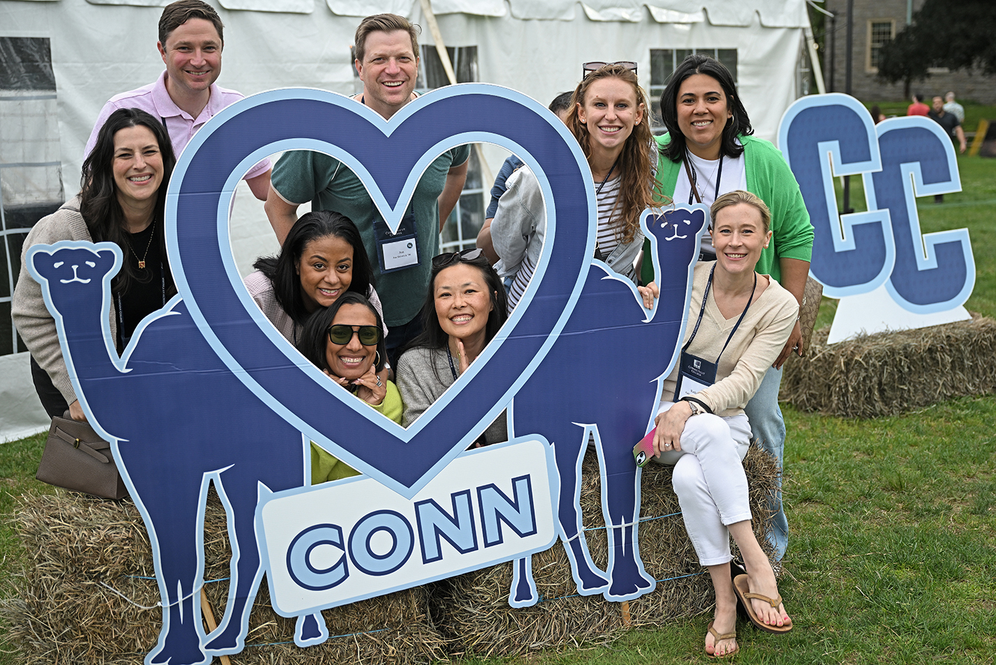 A group of college alumni gather in and around a heart-shaped frame for a photo.
